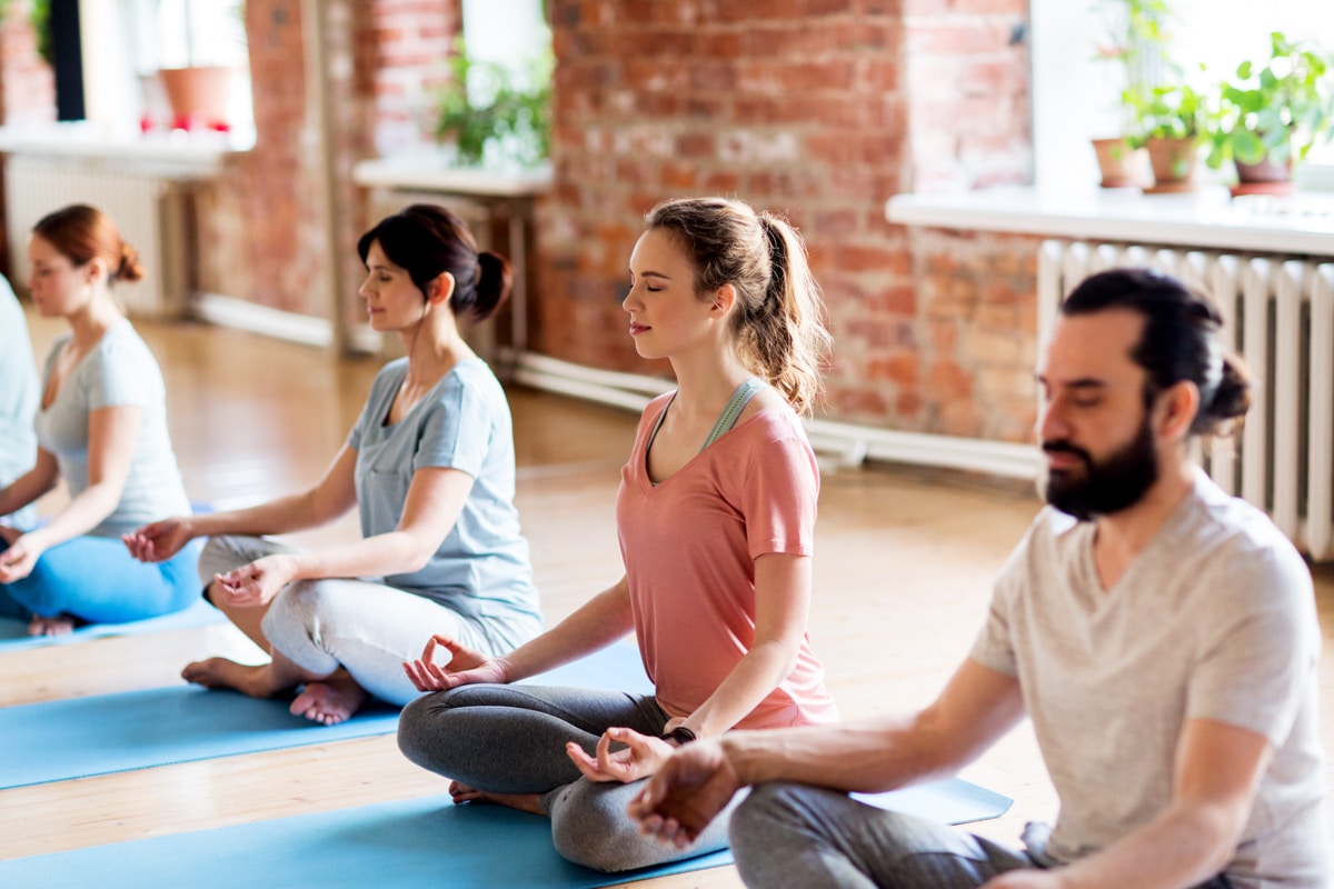 A group of adults meditate during a yoga class