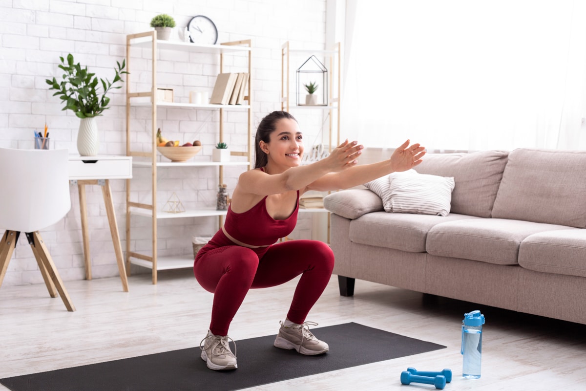 Woman performs extending arm squat in home workout