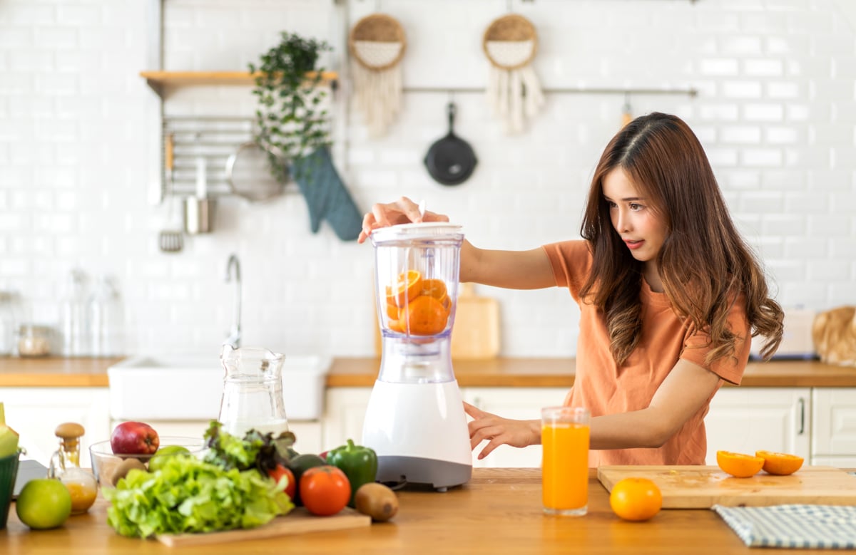 Woman makes orange juice in a blender