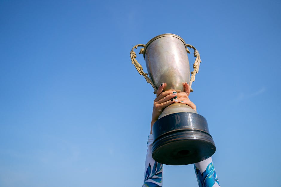 Image description: A picture of a person holding a trophy and smiling, representing the concept of rewards.
